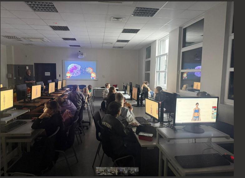 Młode osoby siedzące w pracowni komputerowej