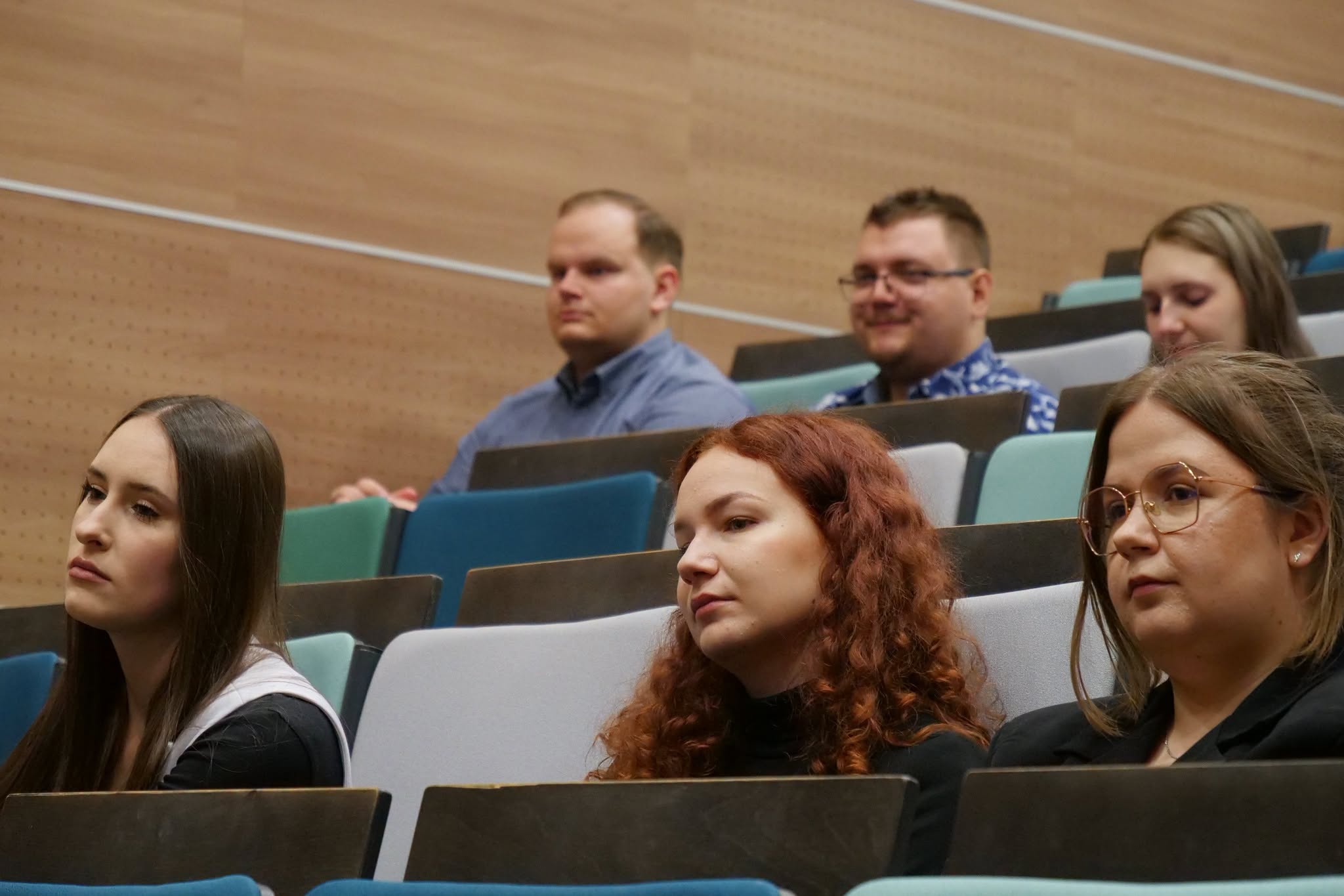 Uczestnicy wydarzenia biorą udział w spotkaniu o charakterze edukacyjnym odbywającym się w sali audytoryjnej. Zgromadzeni słuchają prezentacji, wykładów lub wystąpień związanych z tematyką szkolenia. Wydarzenie sprzyja zdobywaniu wiedzy oraz wymianie doświadczeń między uczestnikami.