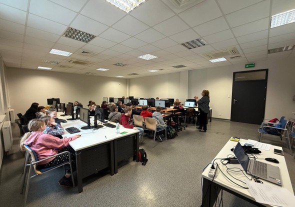 Zdjęcie pracowni komputerowej. Siedzą młode osoby.