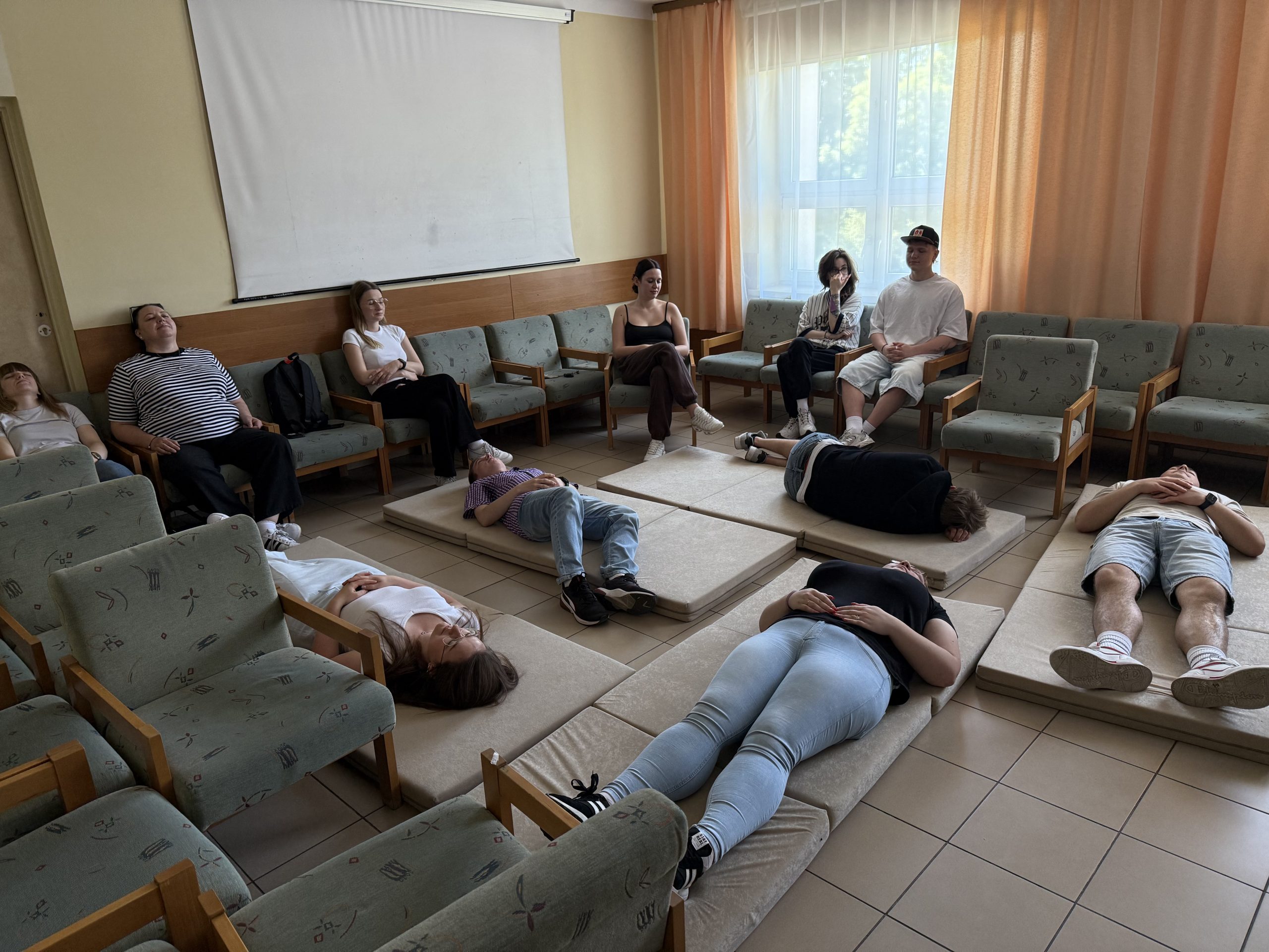 Osoby leżące na ziemi na materacach